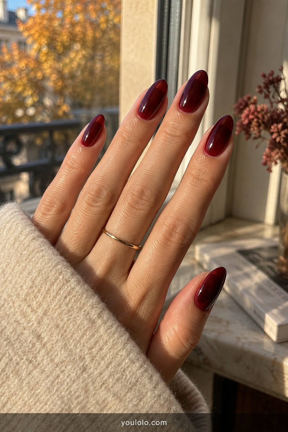 Oxblood glass Fall Almond Nails in natural window light