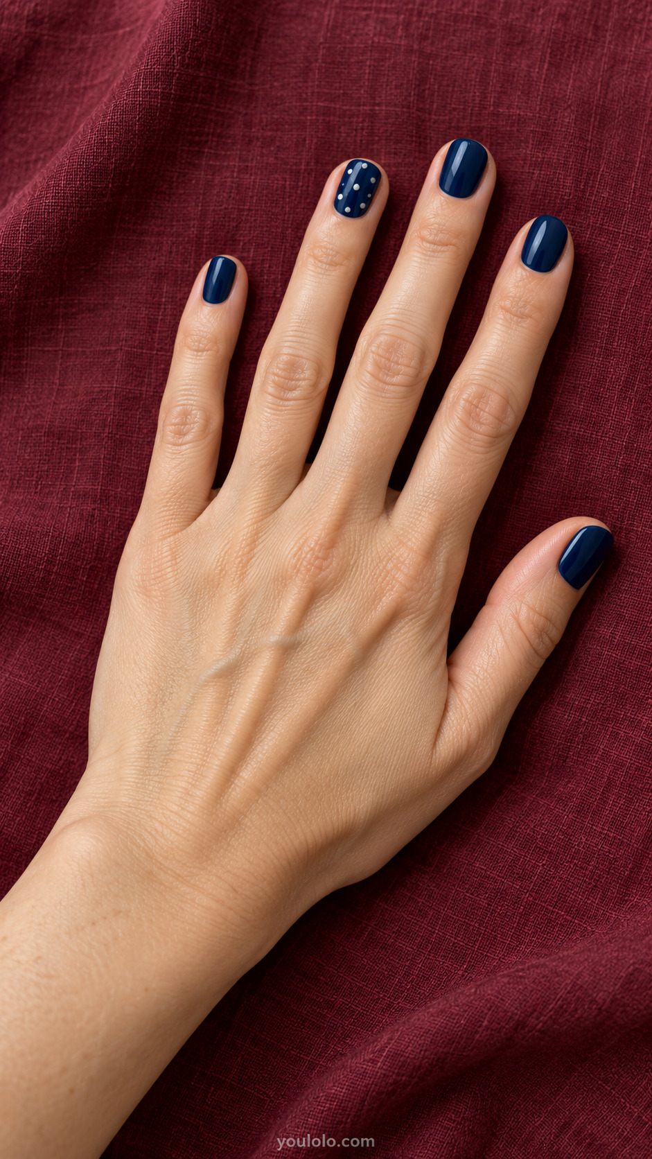 Porcelain Dot Accent — Short round nails; glossy navy set, one ring nail with neatly spaced small warm white dots.