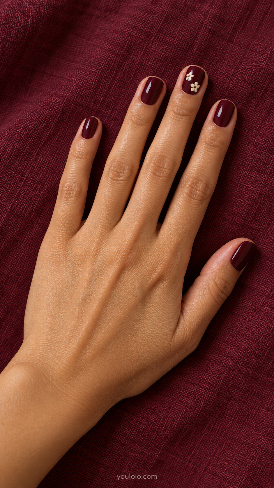 Cream Blossoms on Wine — Short squoval nails; deep burgundy base with two small cream flowers on ring, cream centers, plain others.