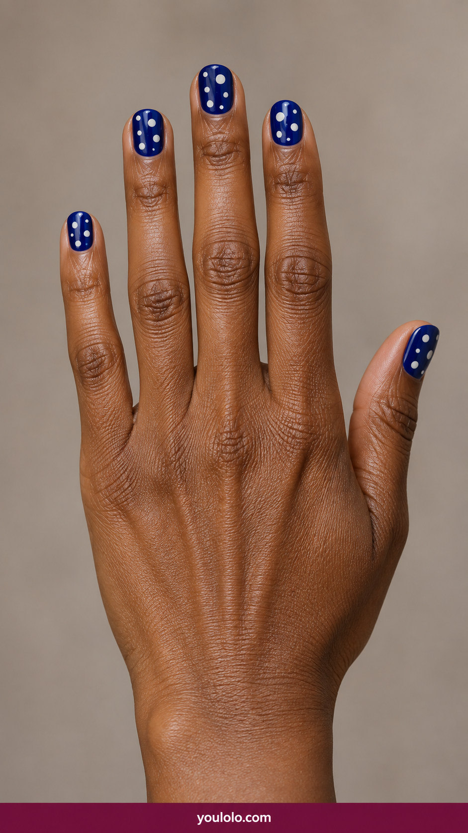 Polka Dot Nails idea 3: short cobalt-blue nails with contrasting crisp ivory dots of two sizes on an anatomically realistic feminine hand