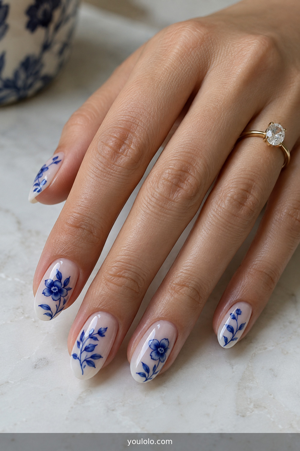 Blue porcelain floral nail art on a milky base