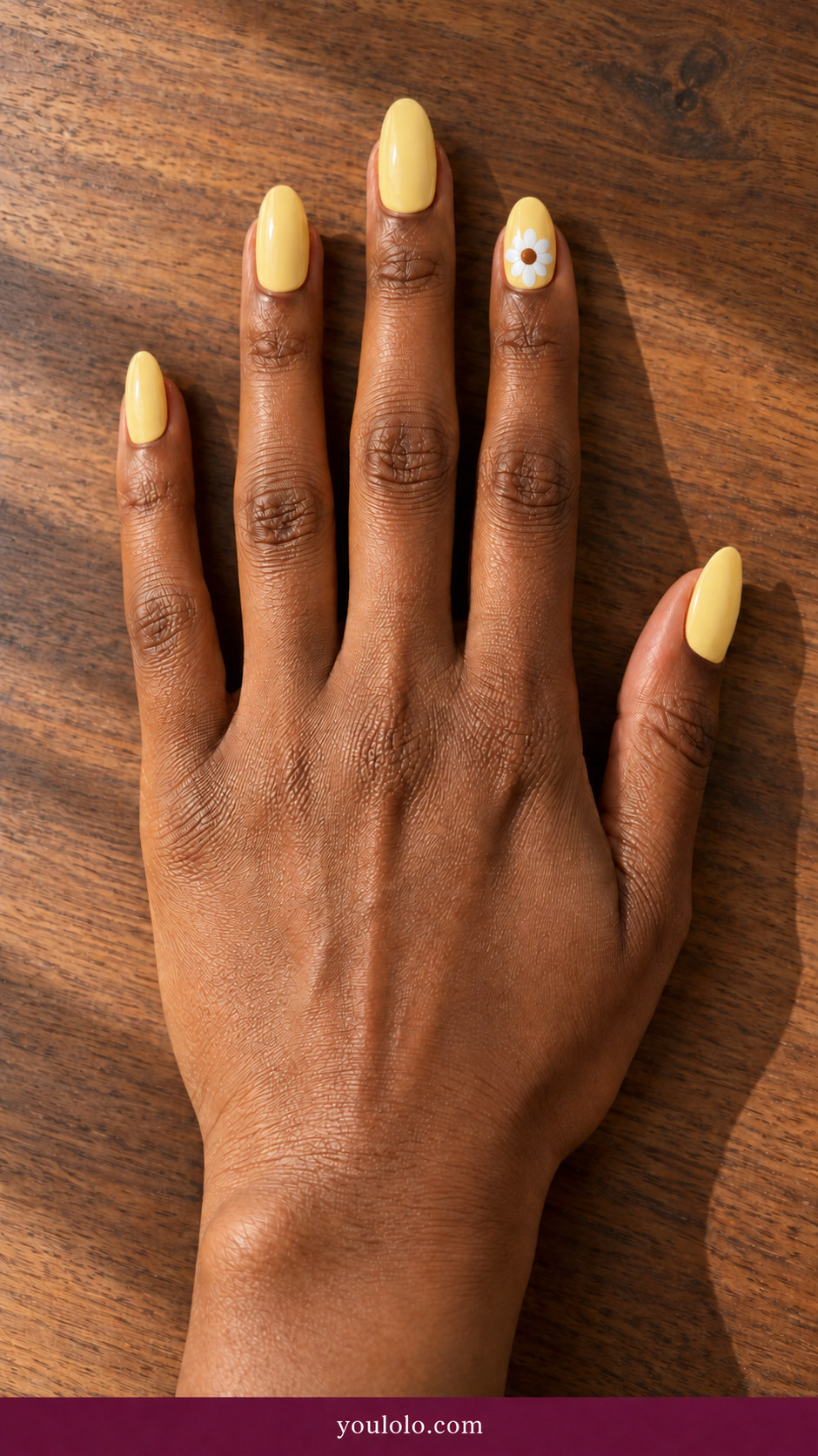 Butter Yellow Nails idea 4: medium almond butter yellow nails with one miniature white daisy accent on an anatomically realistic feminine hand