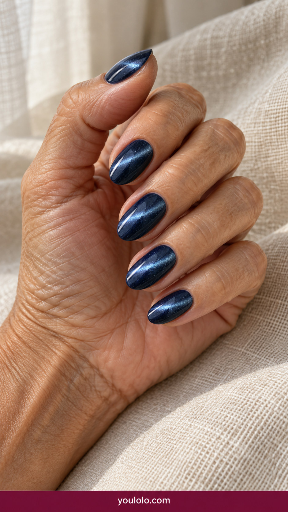 Cat Eye Nails idea 4: navy midnight magnetic cat-eye with pale blue diagonal light band on an anatomically realistic feminine hand