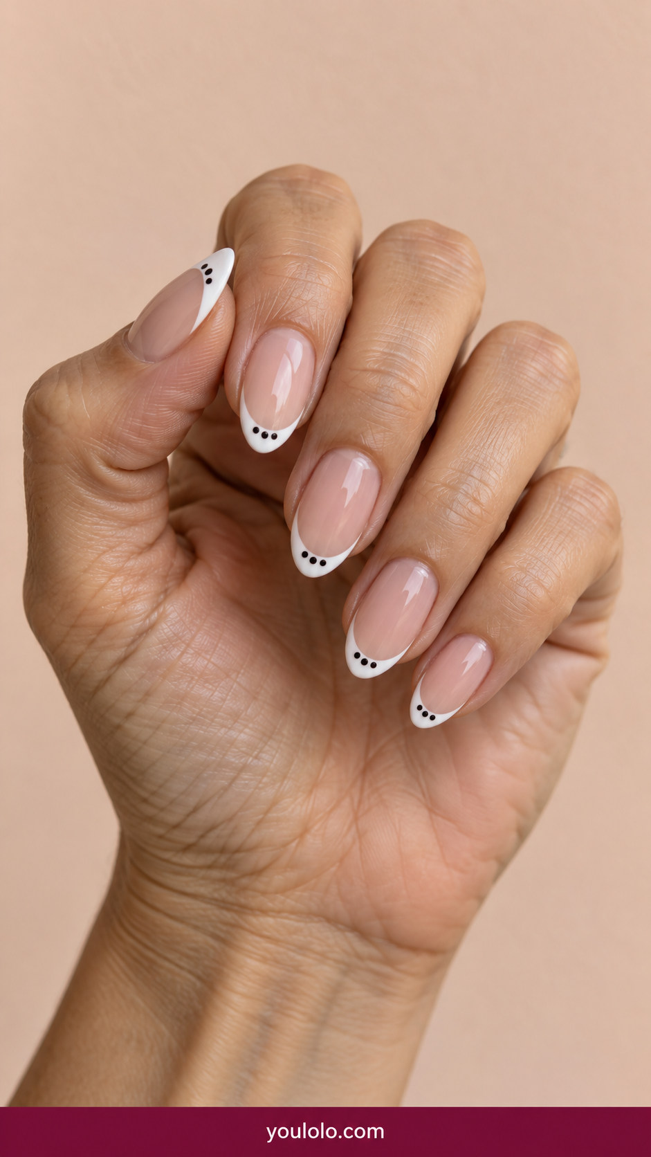 Polka Dot Nails idea 4: nude almond nails with a thin white French tip and three small black dots on each tip on an anatomically realistic feminine hand
