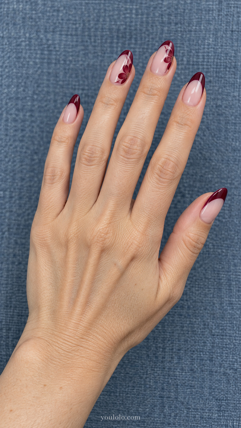 Petal French Edge — Medium almond nails; sheer pink base, burgundy flower petals arranged along French tip boundaries on two nails, plain burgundy other tips.
