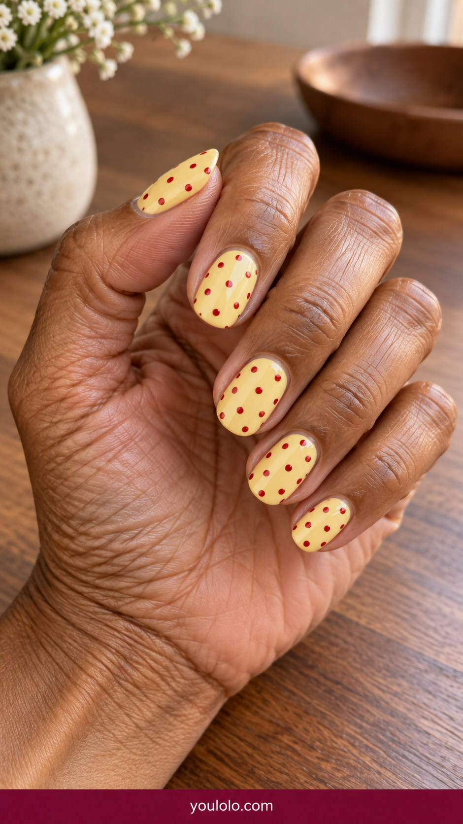 Polka Dot Nails idea 5: butter-yellow rounded nails with small cherry-red retro dots on an anatomically realistic feminine hand