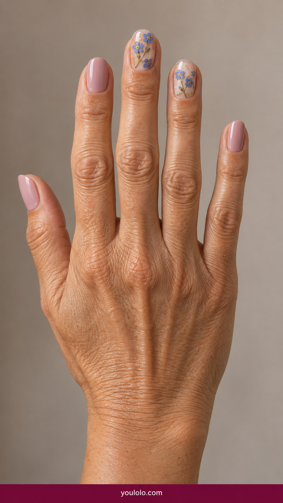 Pressed Flower Nails idea 5: flat pressed blue forget-me-nots individually spaced in clear gel on two accent nails on an anatomically realistic feminine hand