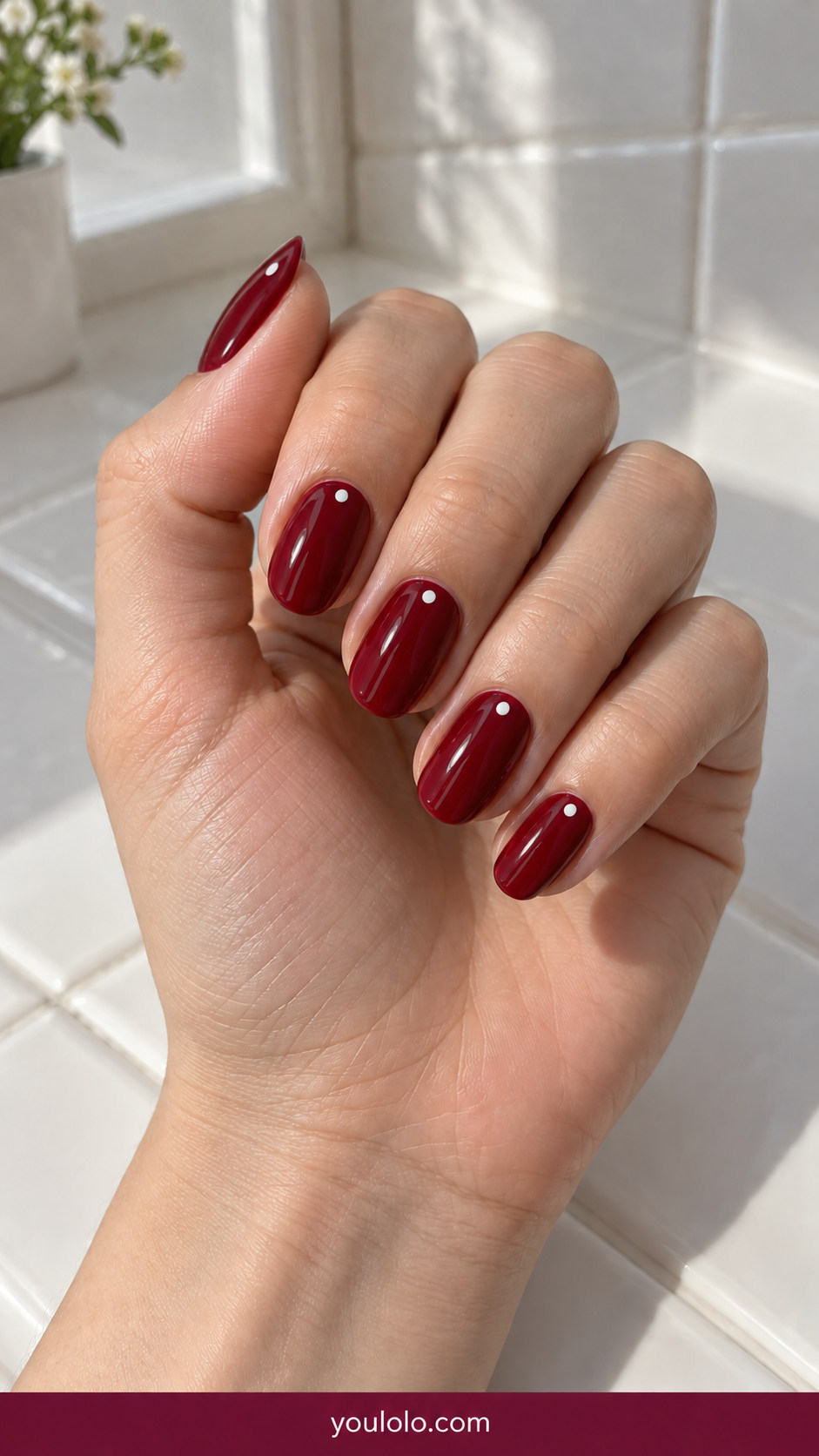 Polka Dot Nails idea 6: glossy deep red nails with delicate white dots near the cuticle only on an anatomically realistic feminine hand
