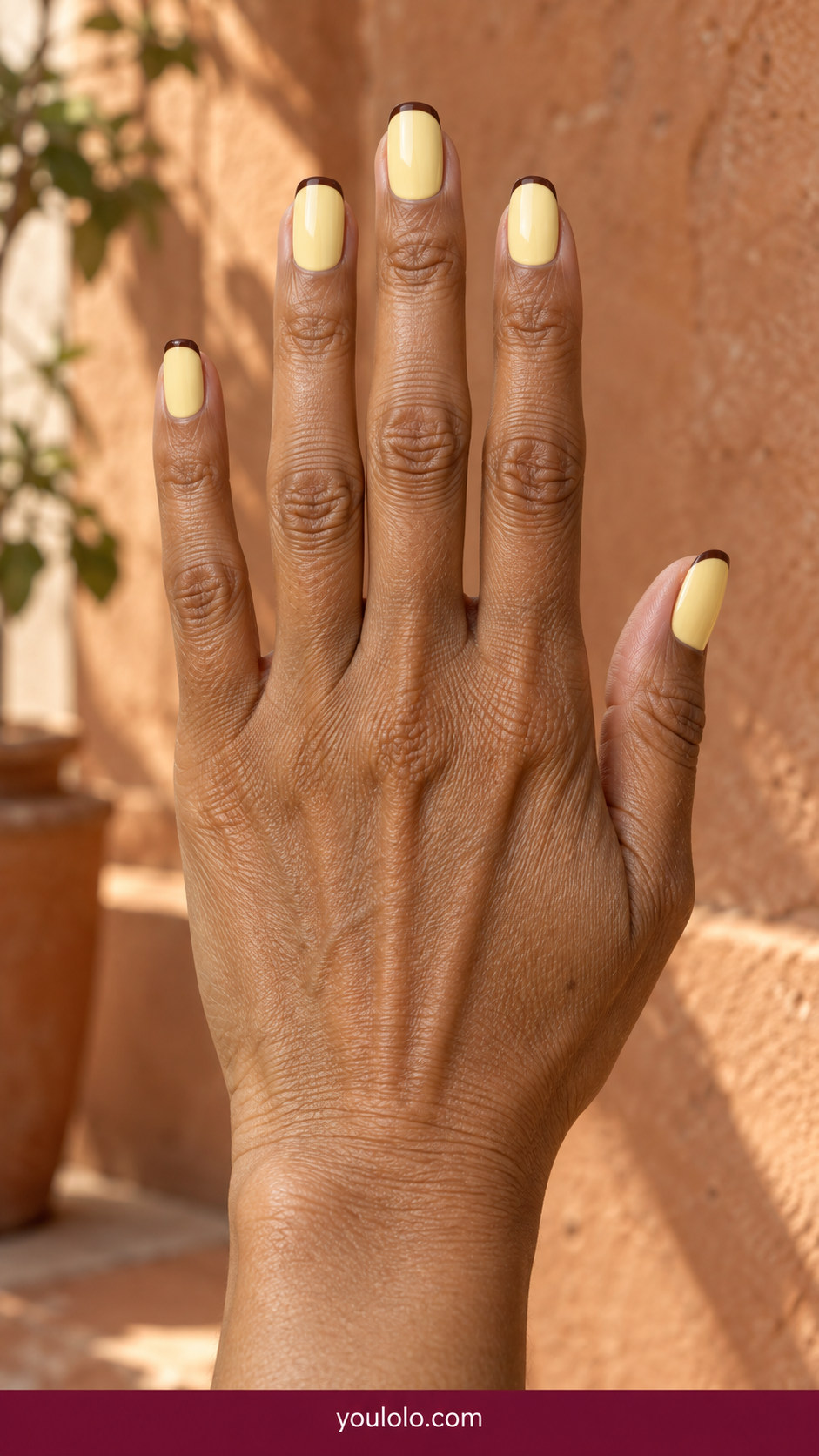 Butter Yellow Nails idea 6: pastel butter-yellow nails with hairline chocolate-brown tips on an anatomically realistic feminine hand