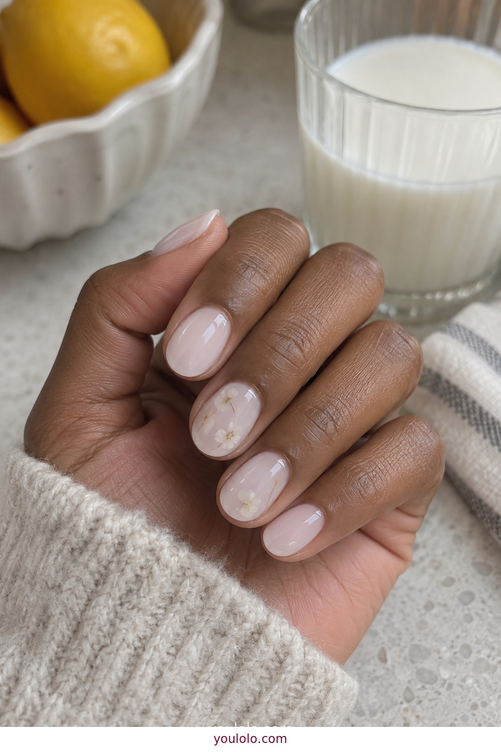 Milk bath manicure with tiny dried white flowers on short nails