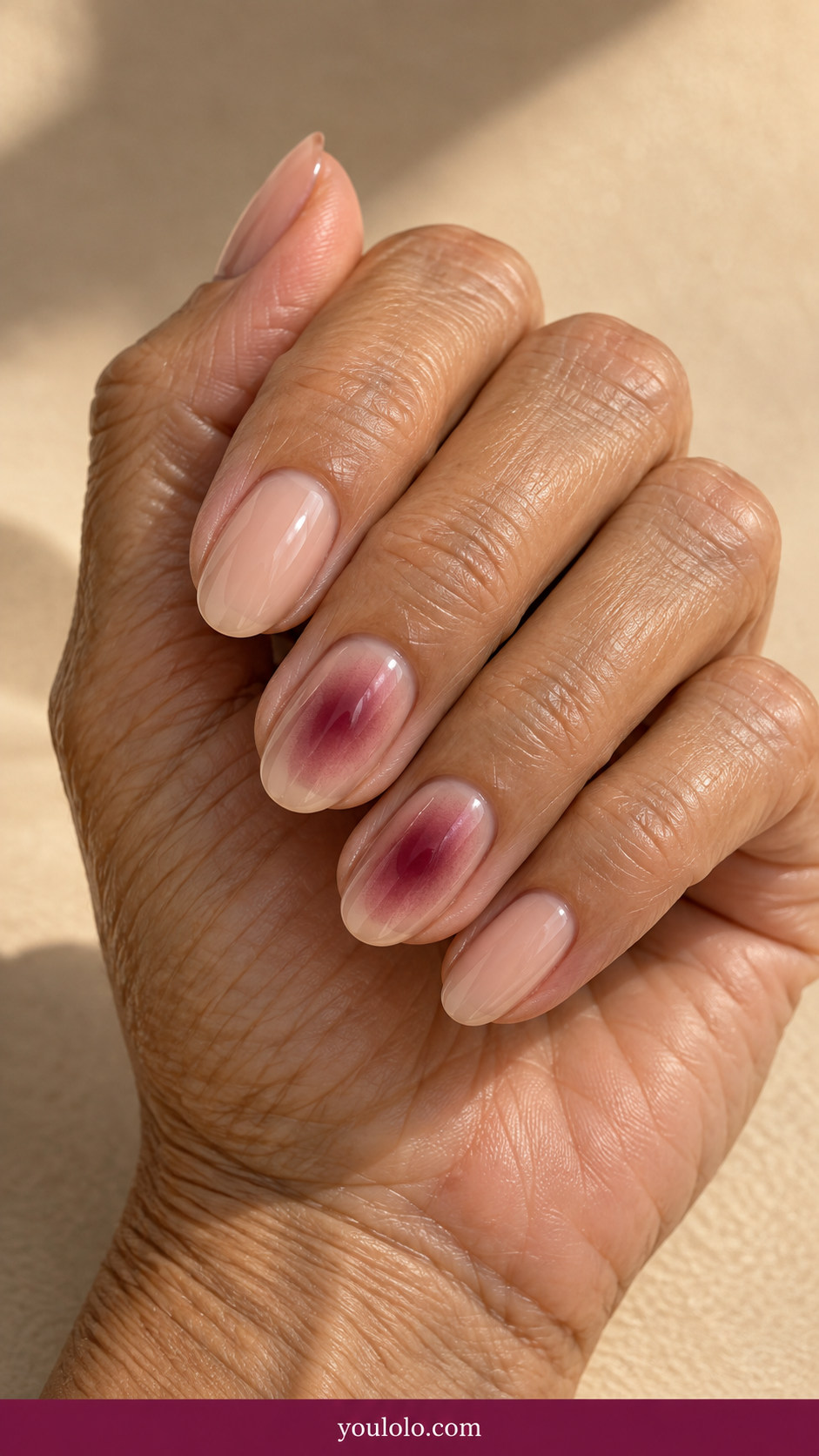 Aura Nails idea 8: sheer beige nails with a muted burgundy aura centered on two accents on an anatomically realistic feminine hand