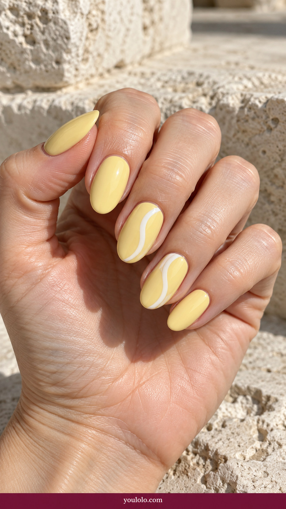 Butter Yellow Nails idea 10: butter-yellow nails with a single white side swirl on two accents on an anatomically realistic feminine hand