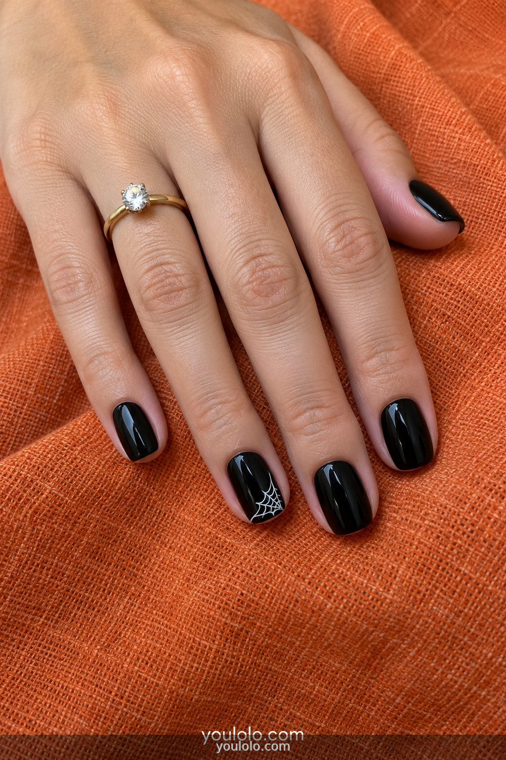 Black manicure with a small white corner cobweb accent