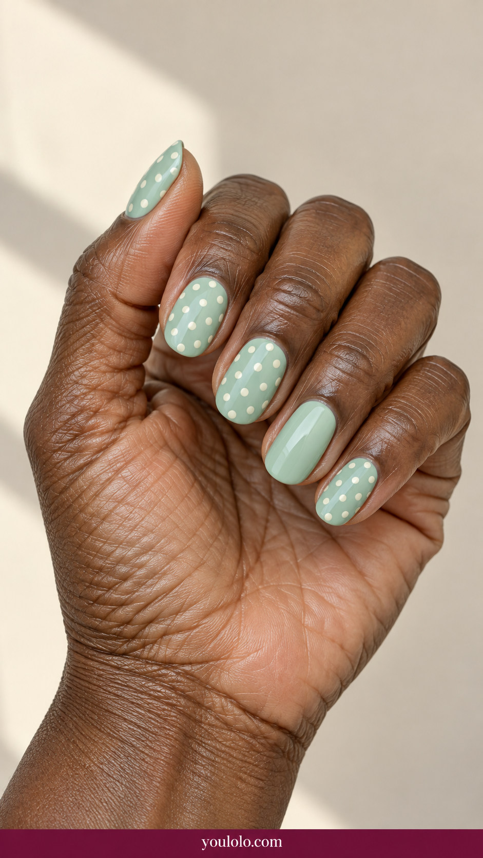 Polka Dot Nails idea 10: soft mint nails with ivory dots and one plain mint accent nail on an anatomically realistic feminine hand