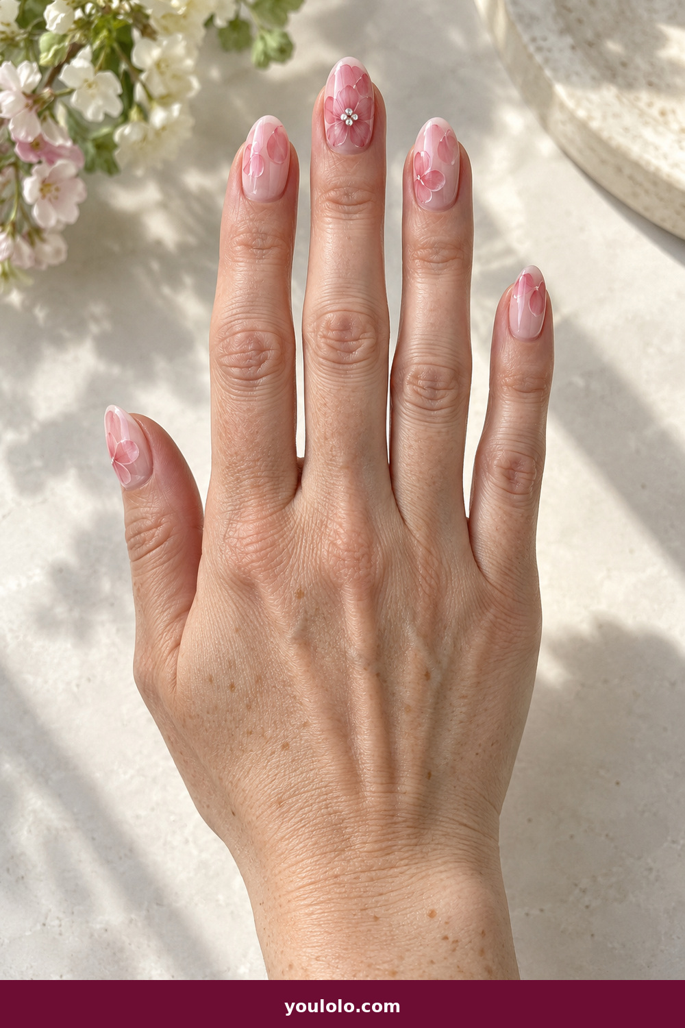 Pink Nails with Rhinestones on One Finger Ideas: Blush Flower Crystal Center, Translucent blush oval nails with painted pink petals and a crystal-centered flower on the middle finger.