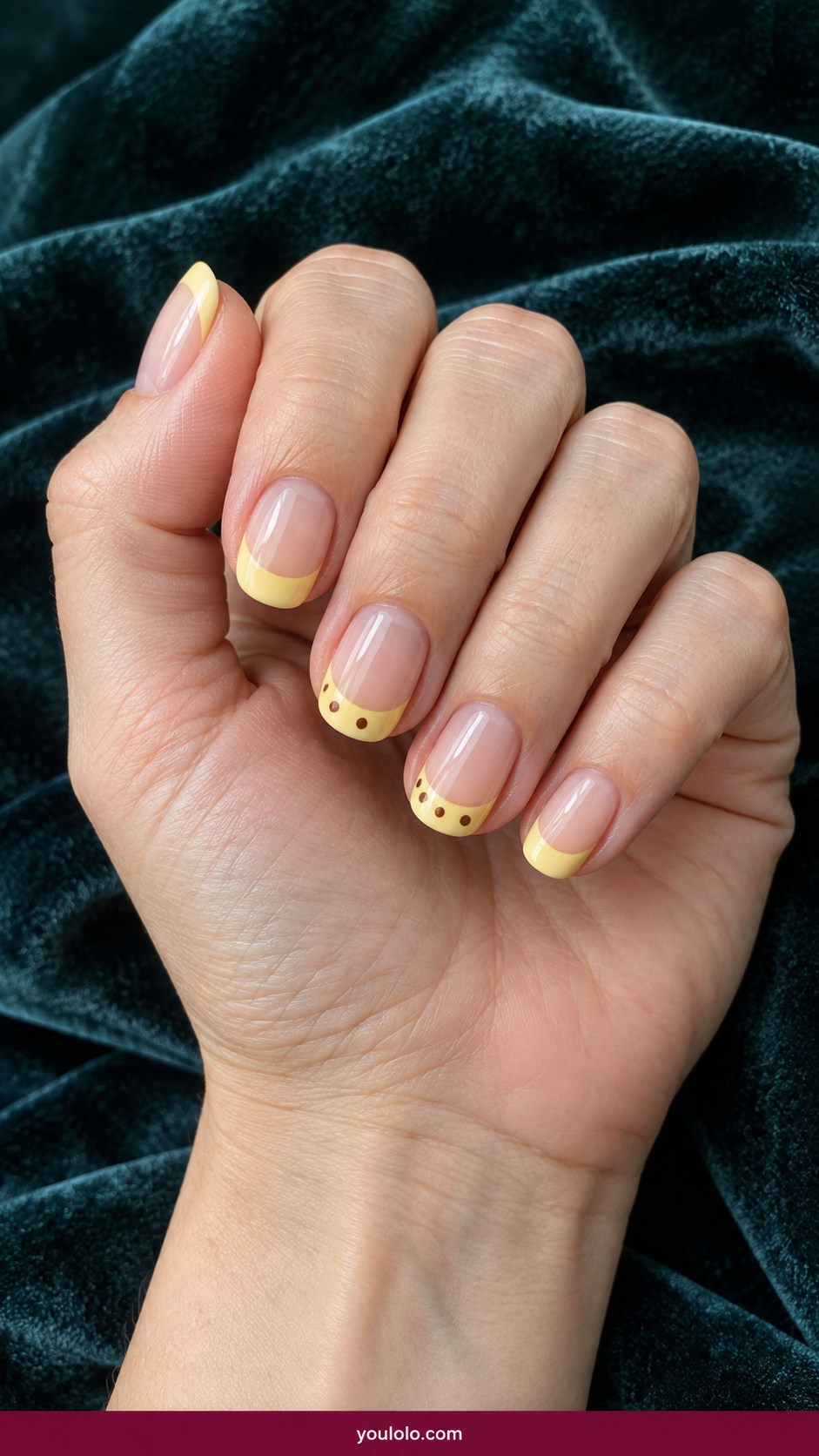 Butter Yellow Nails idea 15: butter-yellow nail tips with tiny brown dots on two French tips on an anatomically realistic feminine hand