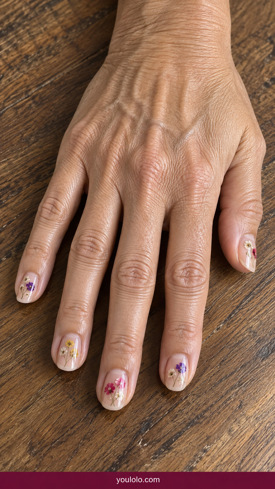 Pressed Flower Nails idea 15: scattered micro dried flowers embedded near cuticles of sheer nude nails on an anatomically realistic feminine hand