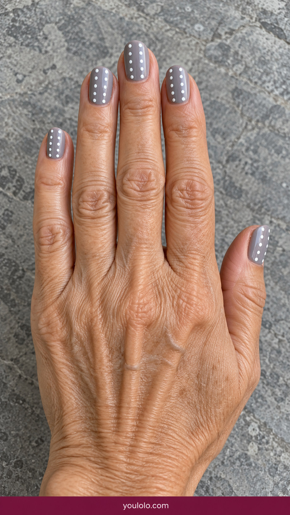 Polka Dot Nails idea 15: soft gray nails with two neat vertical columns of white dots on an anatomically realistic feminine hand