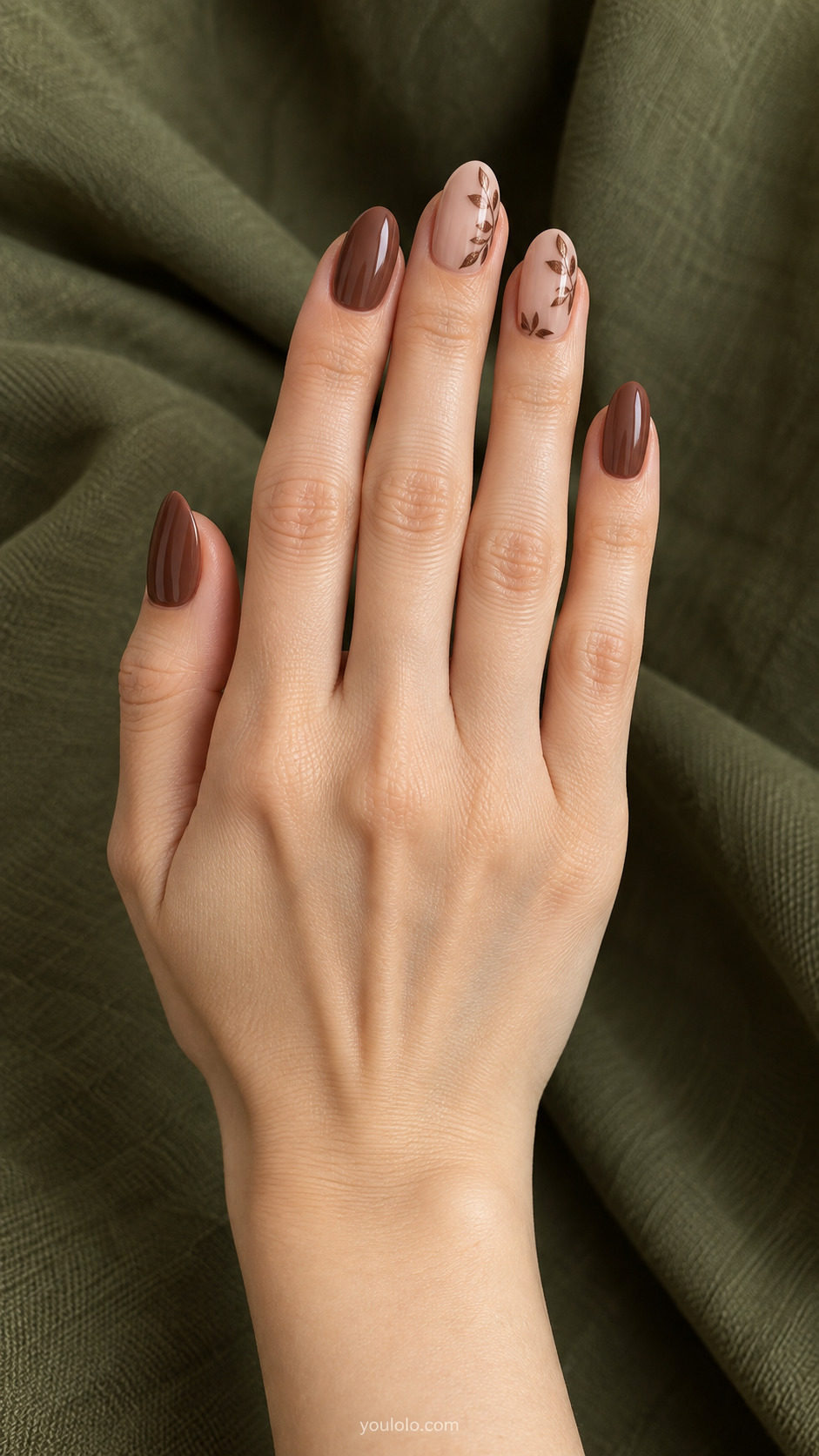 Bronze Botanical Border — Medium almond nails; sheer beige base, fine bronze leaves tracing a partial border on two nails, cocoa plain others.