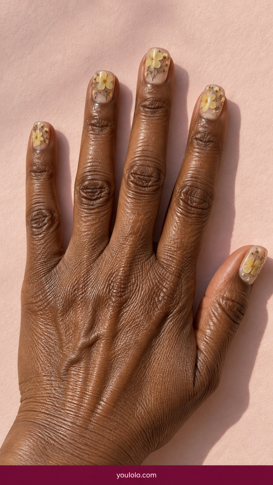 Pressed Flower Nails idea 16: flat dried butter-yellow petals inside transparent tips on short squares on an anatomically realistic feminine hand