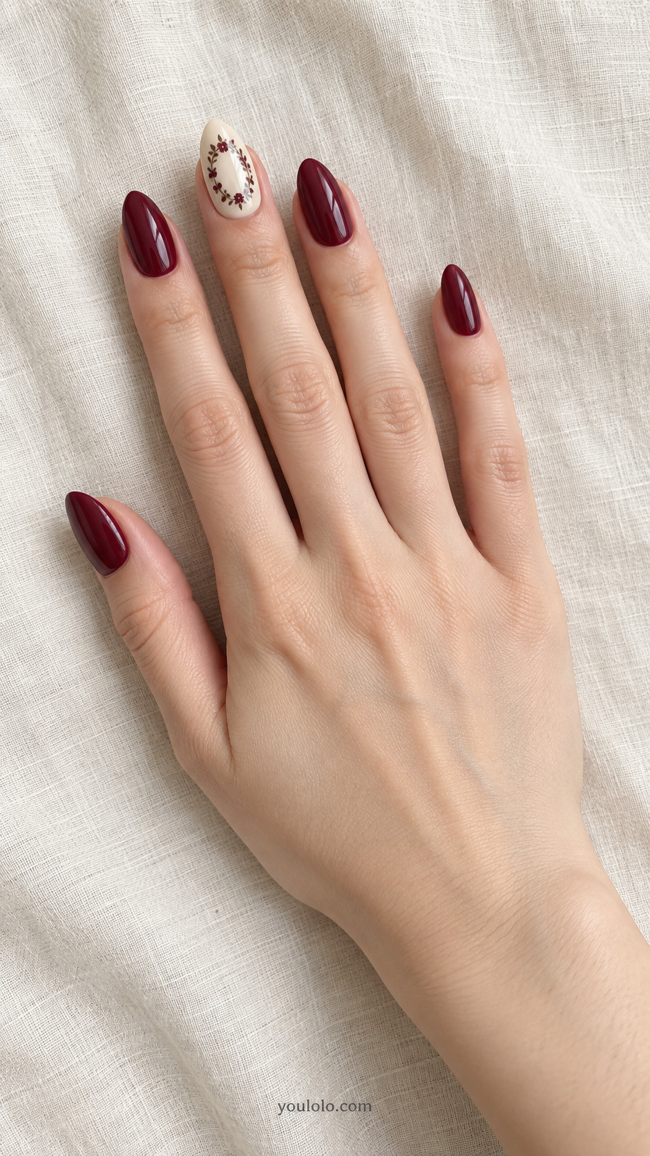 Burgundy Floral Medallion — Medium almond nails; cream ring with a small oval wine floral wreath, tiny cream center, burgundy solids.