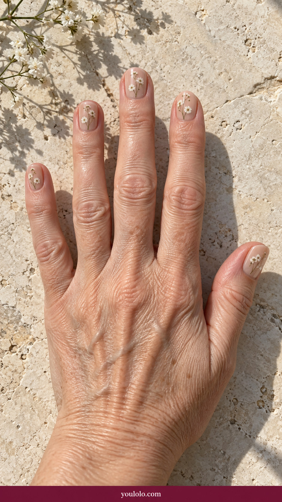 Pressed Flower Nails idea 19: very fine pressed white flower silhouettes on short glossy beige nails on an anatomically realistic feminine hand