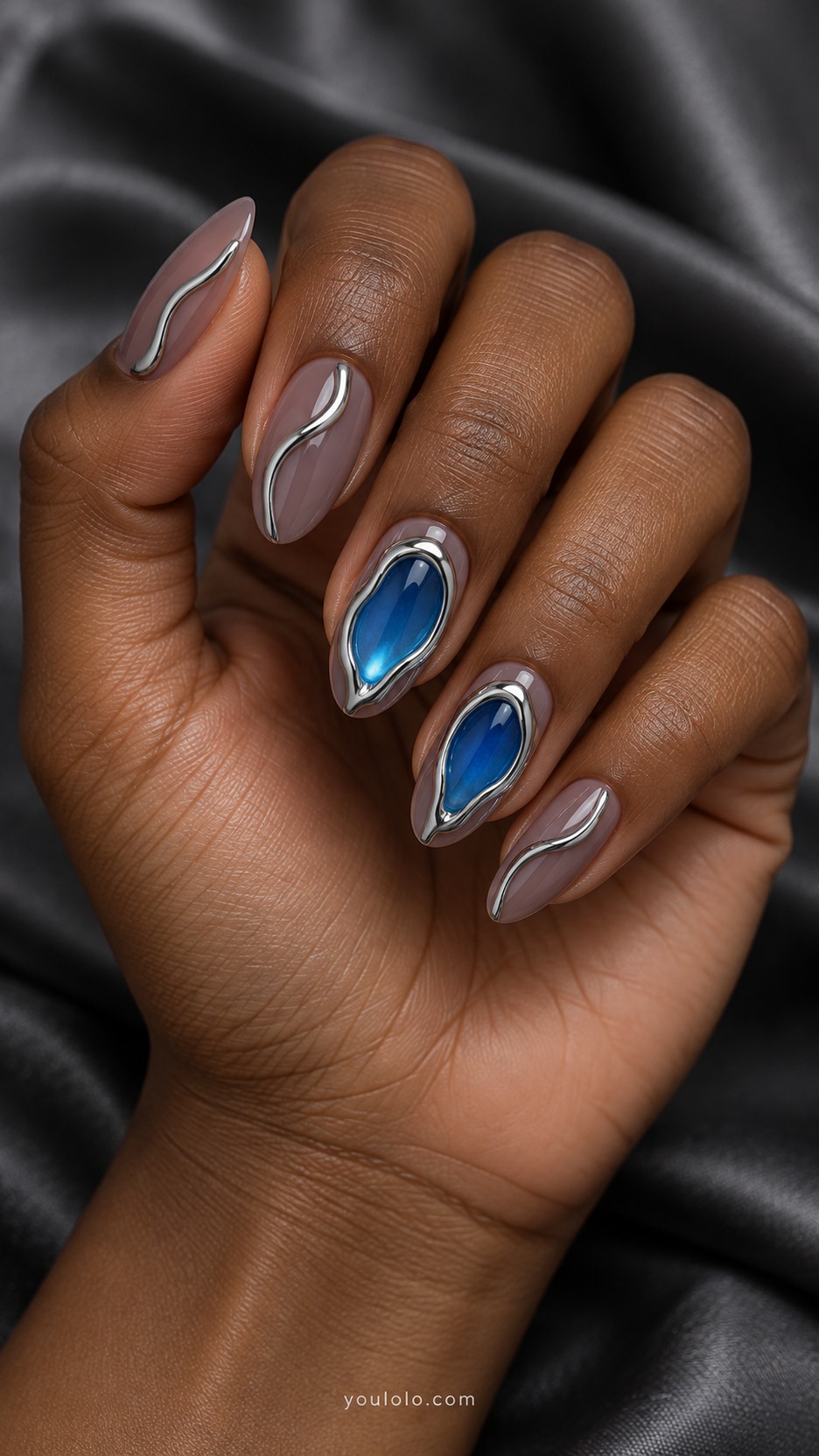 Liquid-Silver Portal Nails — Medium almond nails, sheer smoky mauve base, two accent nails with raised irregular oval silver-chrome frames enclosing translucent electric-blue centers
