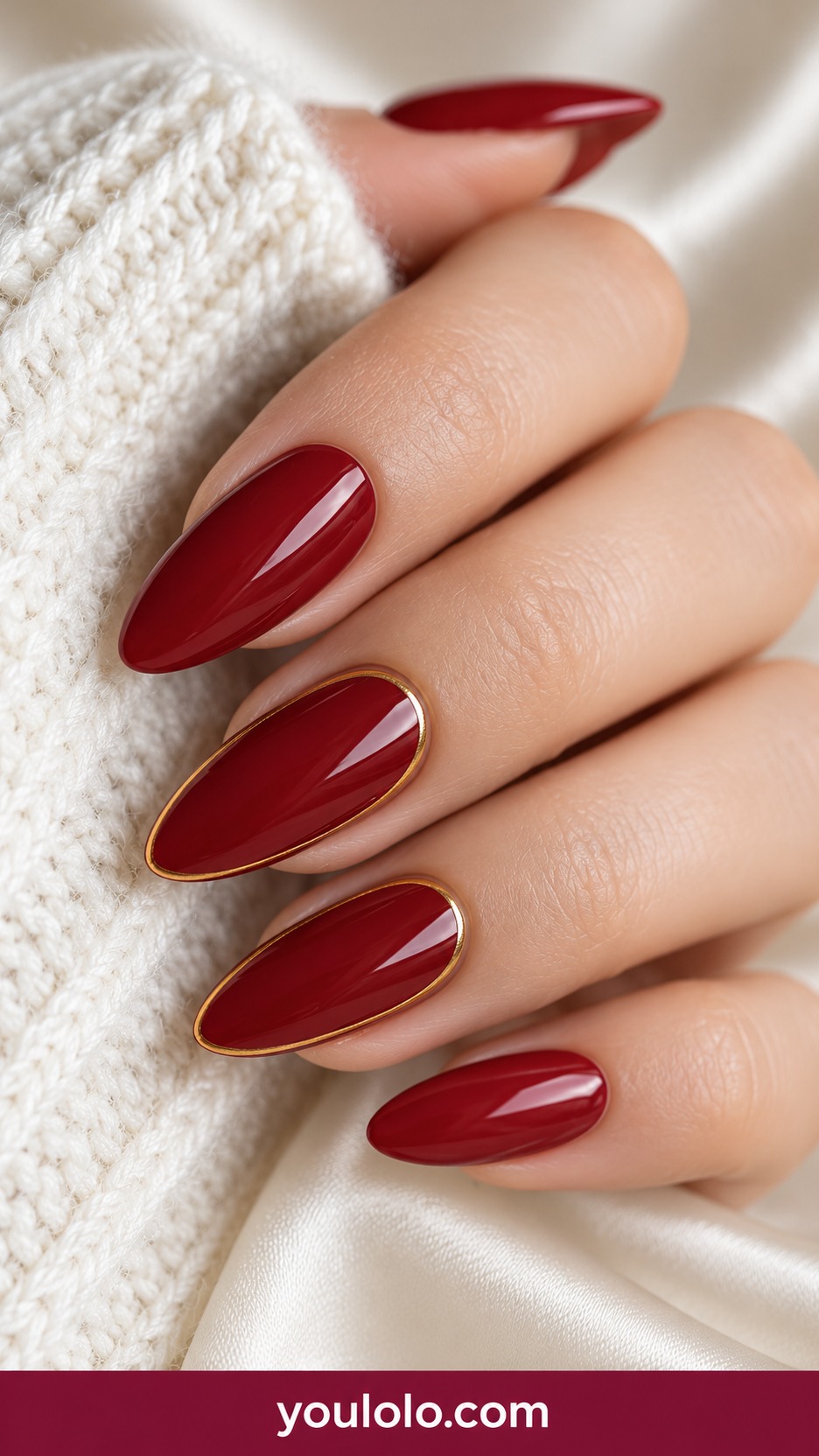 Medium almond deep crimson nails with very fine gold perimeter border on two accents on a naturally curled young adult hand