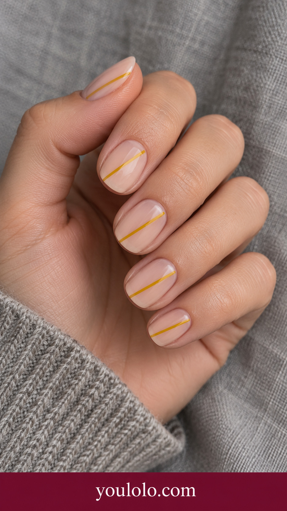 Mustard Diagonal: short squoval sheer beige nails one fine mustard yellow diagonal stripe on each nail on a naturally posed adult hand