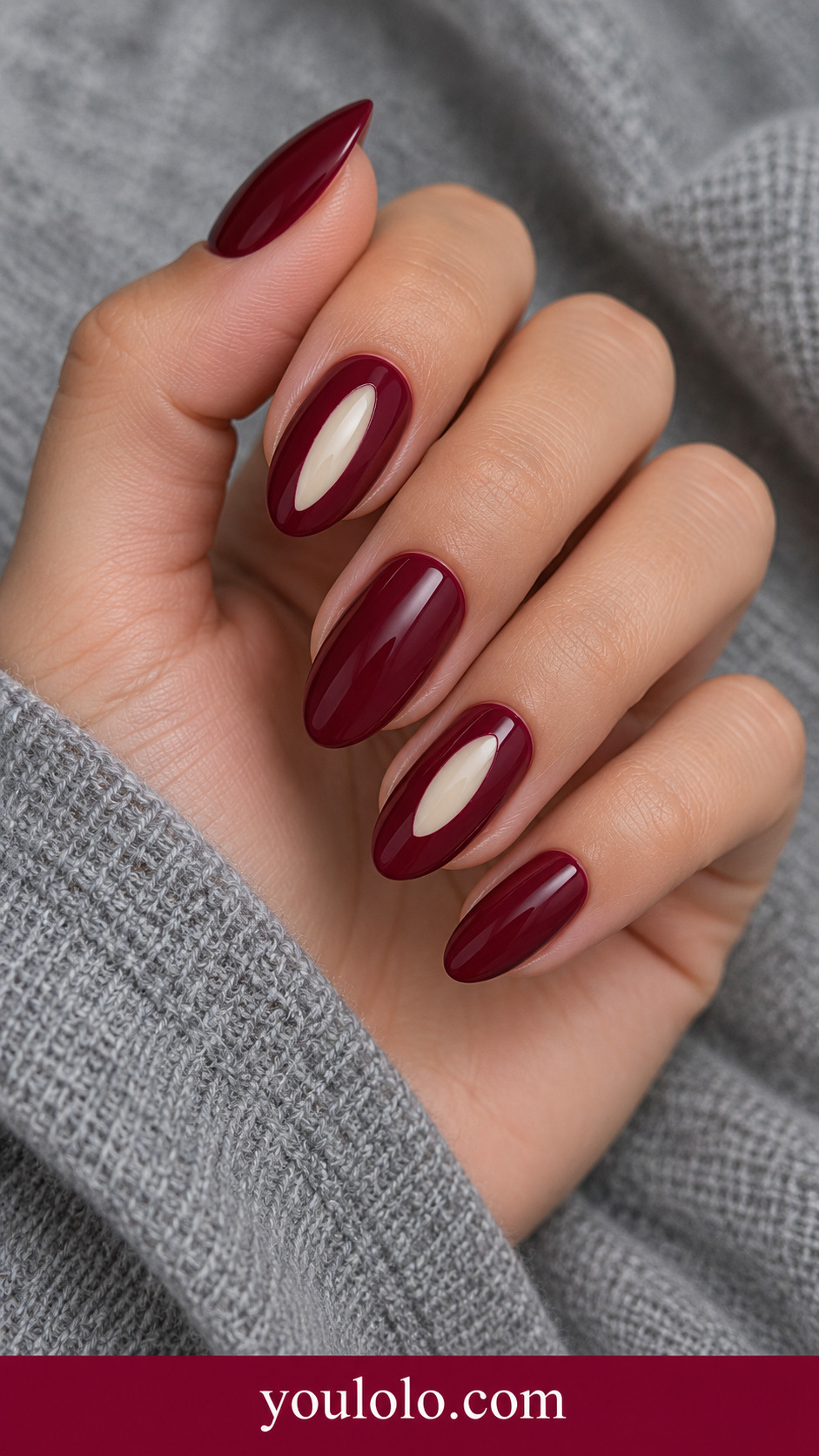Maroon Ivory Aperture: medium almond deep maroon nails index and ring small clean vertical ivory oval windows centered in nail on a naturally posed adult hand