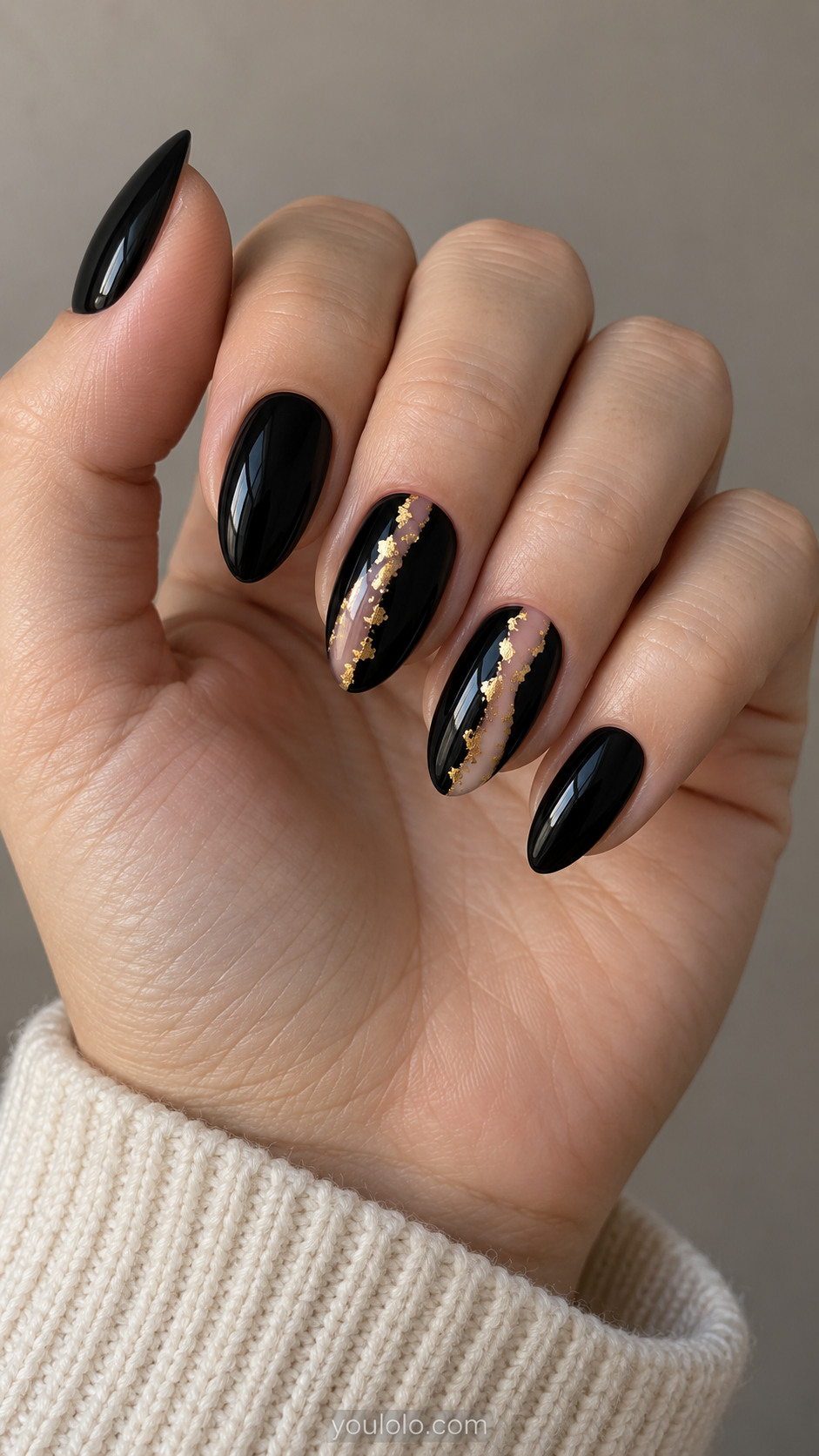 Black almond nails with nude vertical openings edged in irregular gold foil