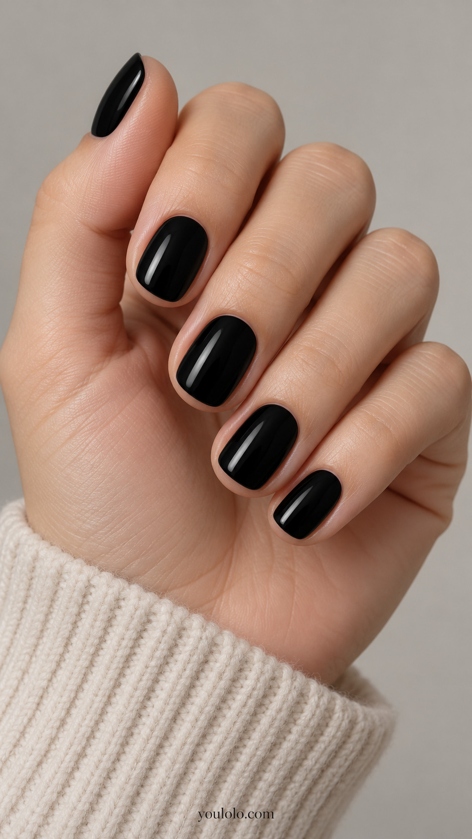 Short glossy black squoval nails on a relaxed hand