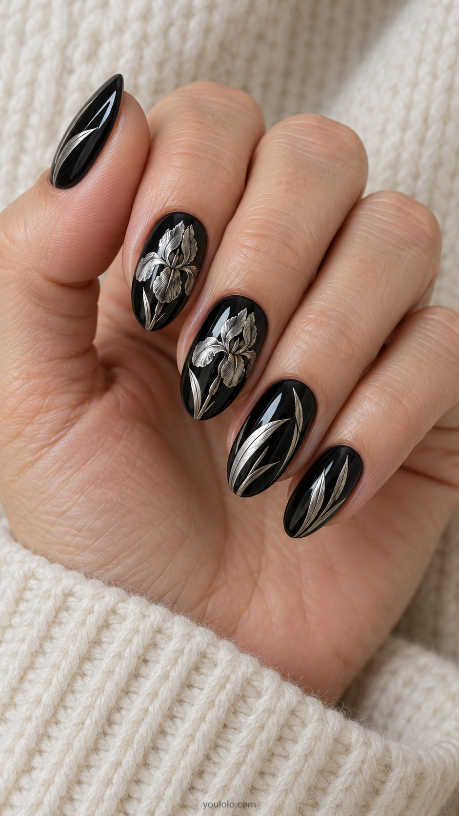 Medium almond glossy black nails with intricate metallic silver iris flower engraving-style fine linework across two nails, slim silver leaf blades on others