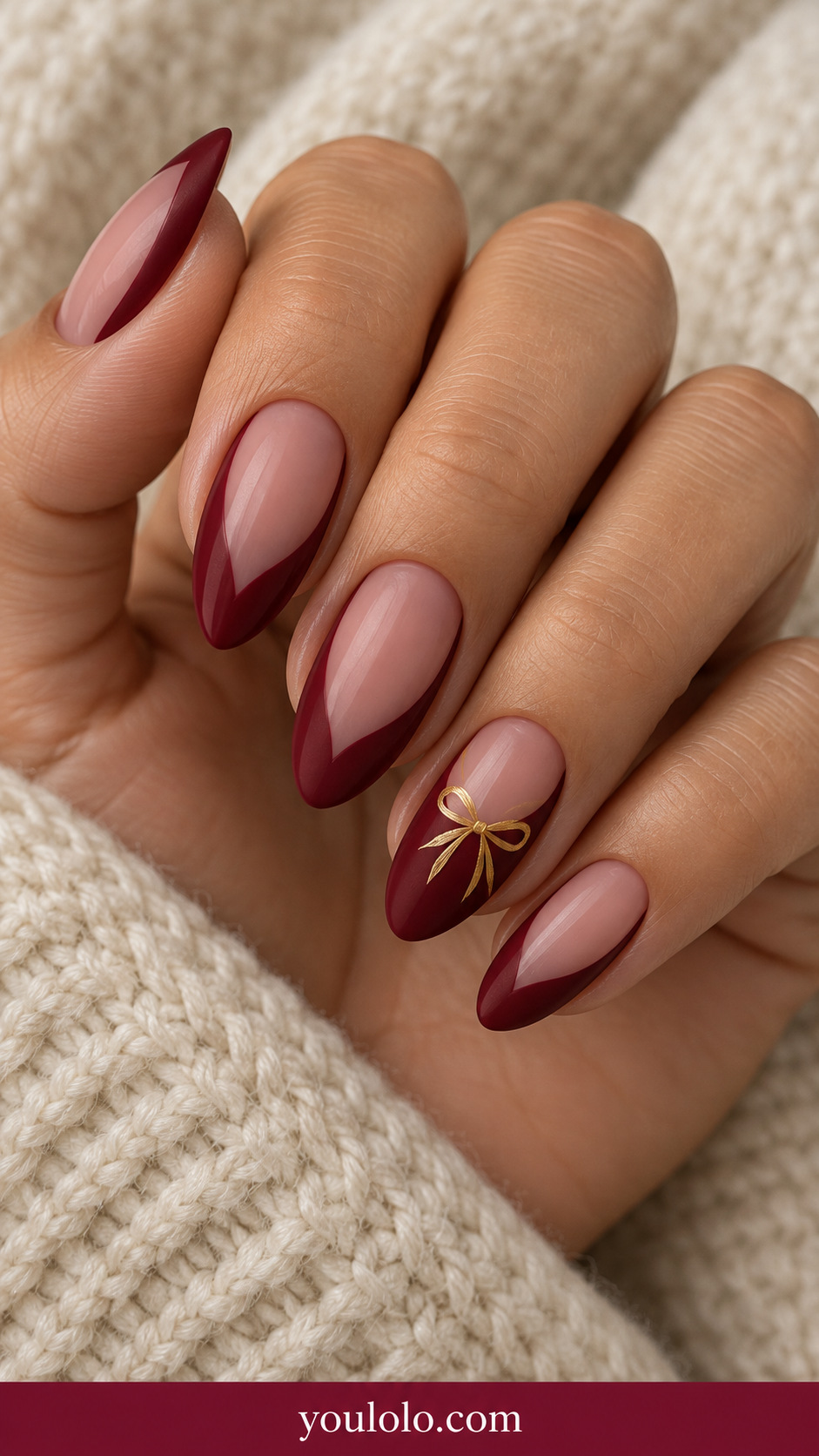 medium almond sheer blush center with deep red curved border at side and tip, tiny flat gold ribbon bow on ring nail only on a naturally relaxed adult hand