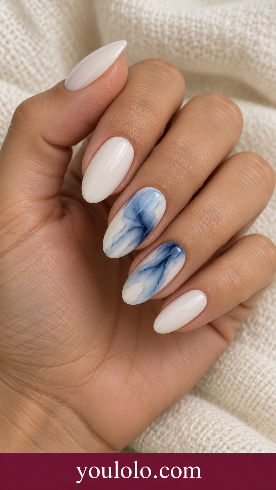 Blue Tide Marble: medium almond ivory nails two accents flowing translucent navy and pale blue blooming marble streams on a naturally posed adult hand