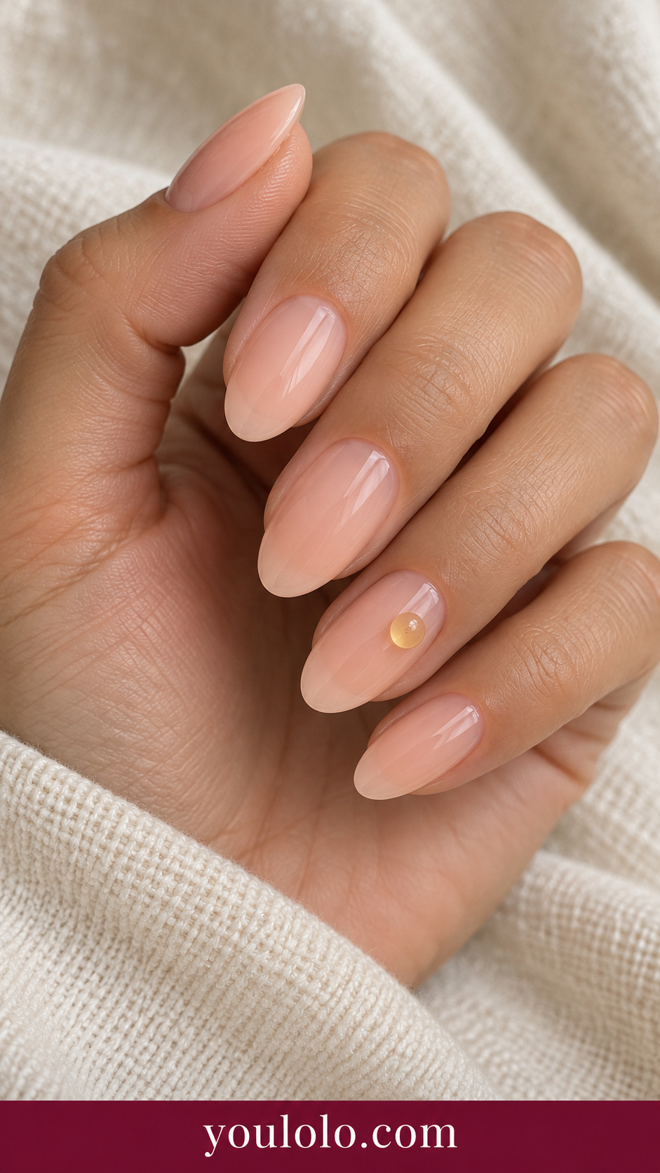 Jelly Citrus Dot: medium oval sheer peach nails one small translucent yellow raised rounded gel dot on ring nail on a naturally posed adult hand