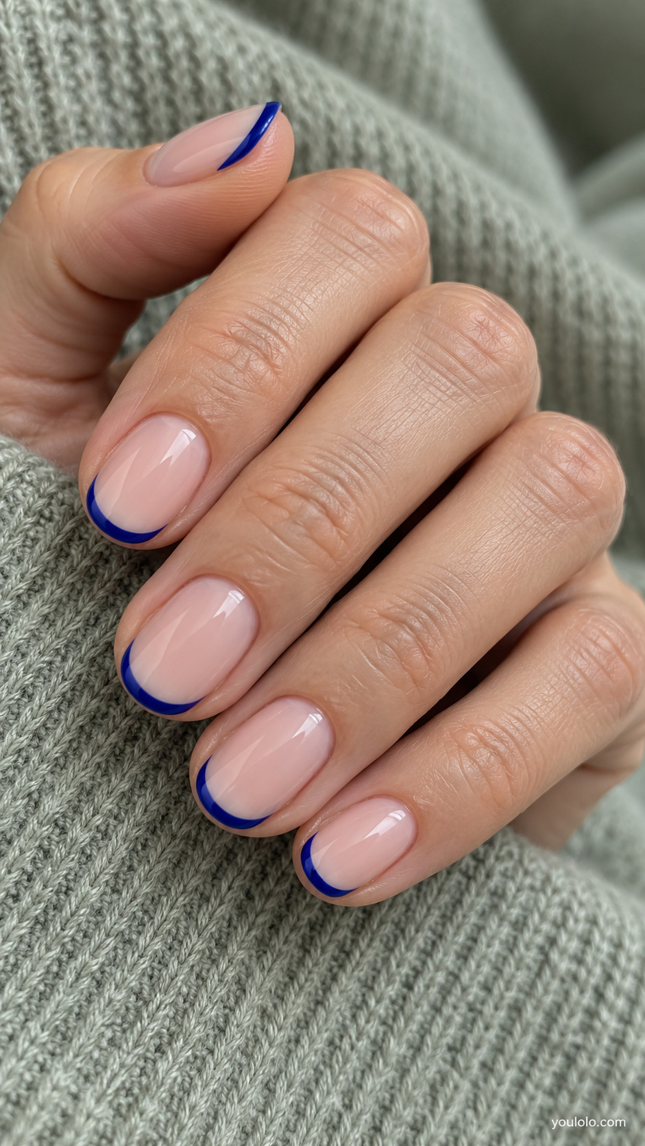 Short nude pink oval nails with narrow royal blue French tips