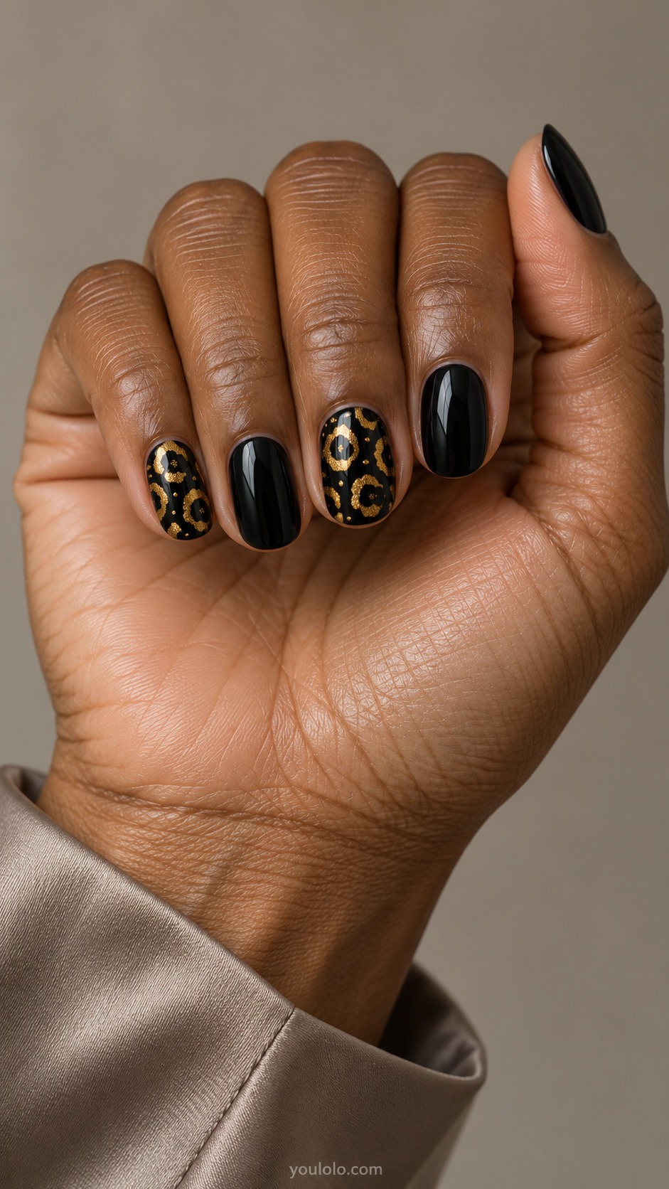 Short black oval nails with two metallic gold leopard-print accents