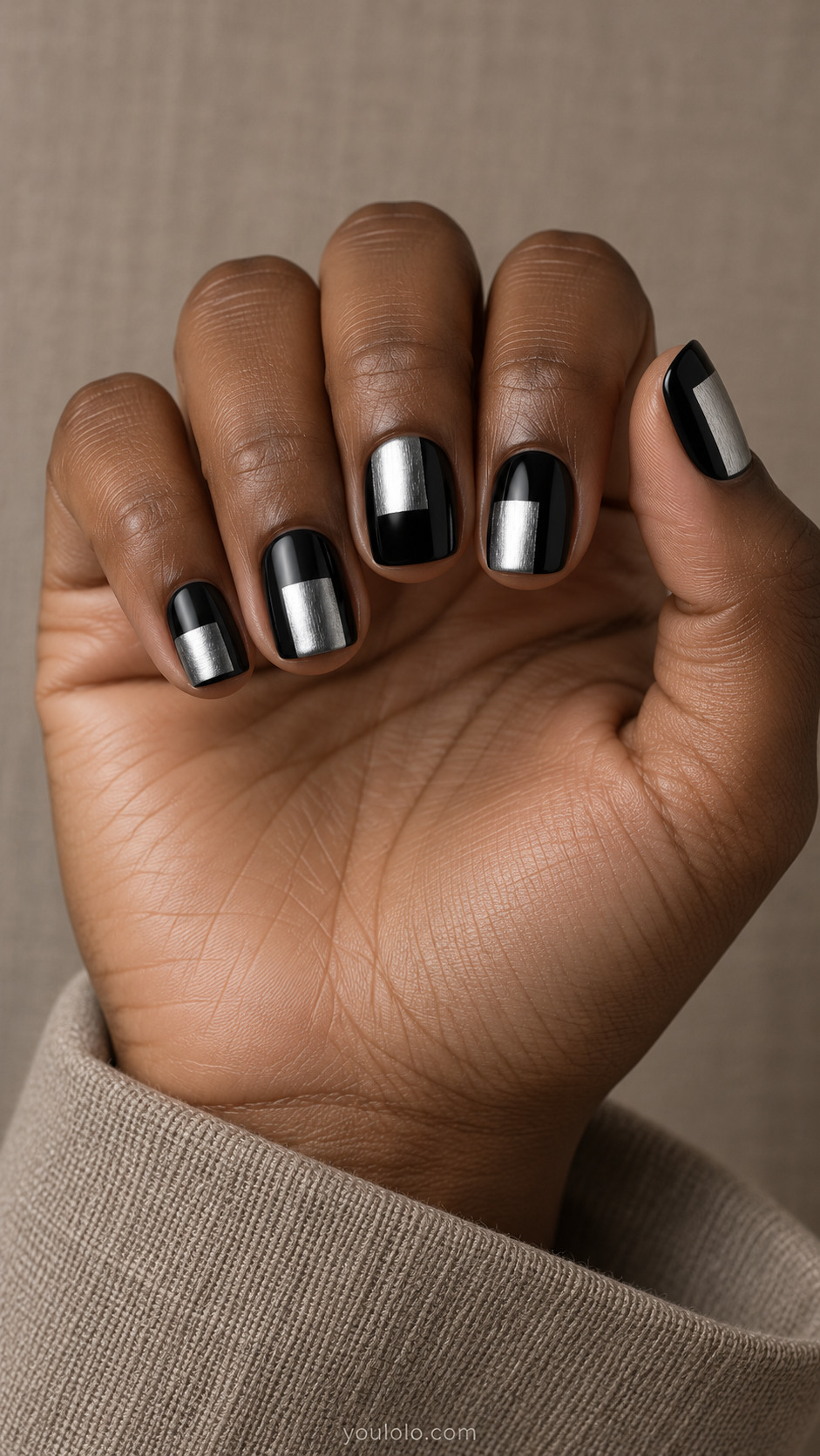 Short squoval black nails with broad asymmetric brushed-silver rectangular blocks placed at different heights, crisp edges, metallic fine grain
