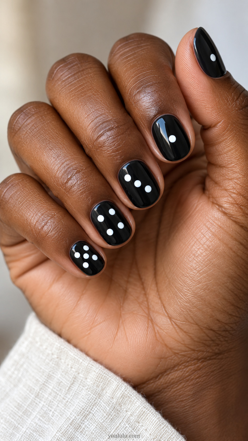 Short glossy black nails with white domino-style dot groups