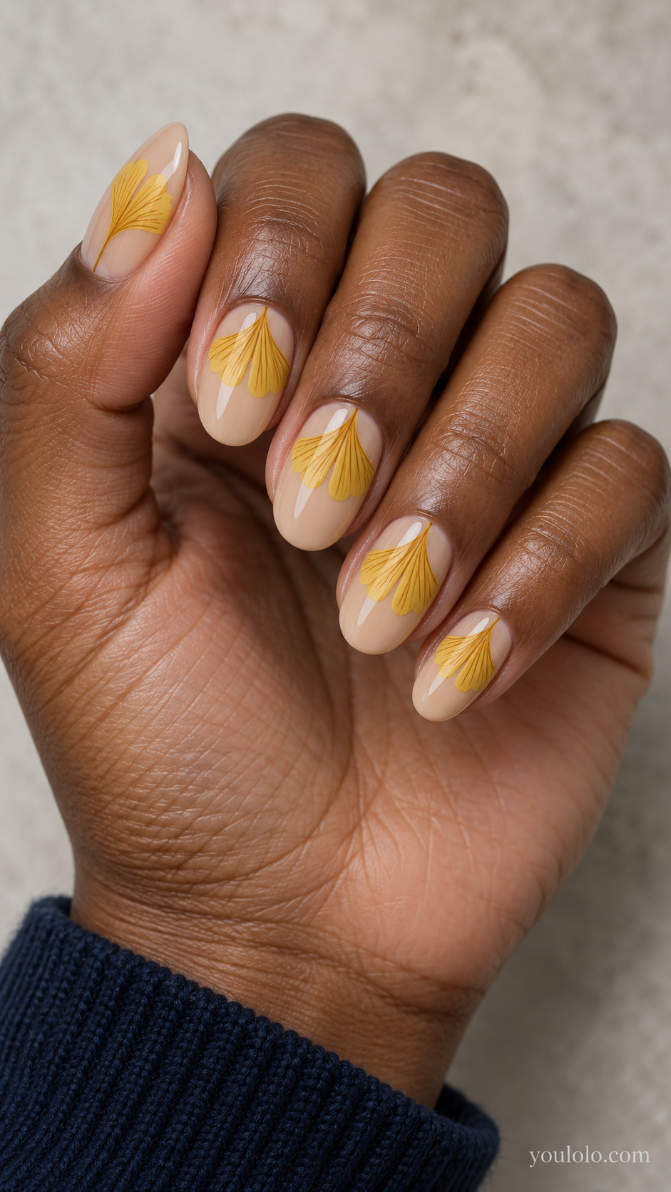 Medium oval nails with sheer beige nails with flat mustard yellow ginkgo fan shapes opening outward from the cuticle half moons, fine dark ochre radial veins, no metallic gold.