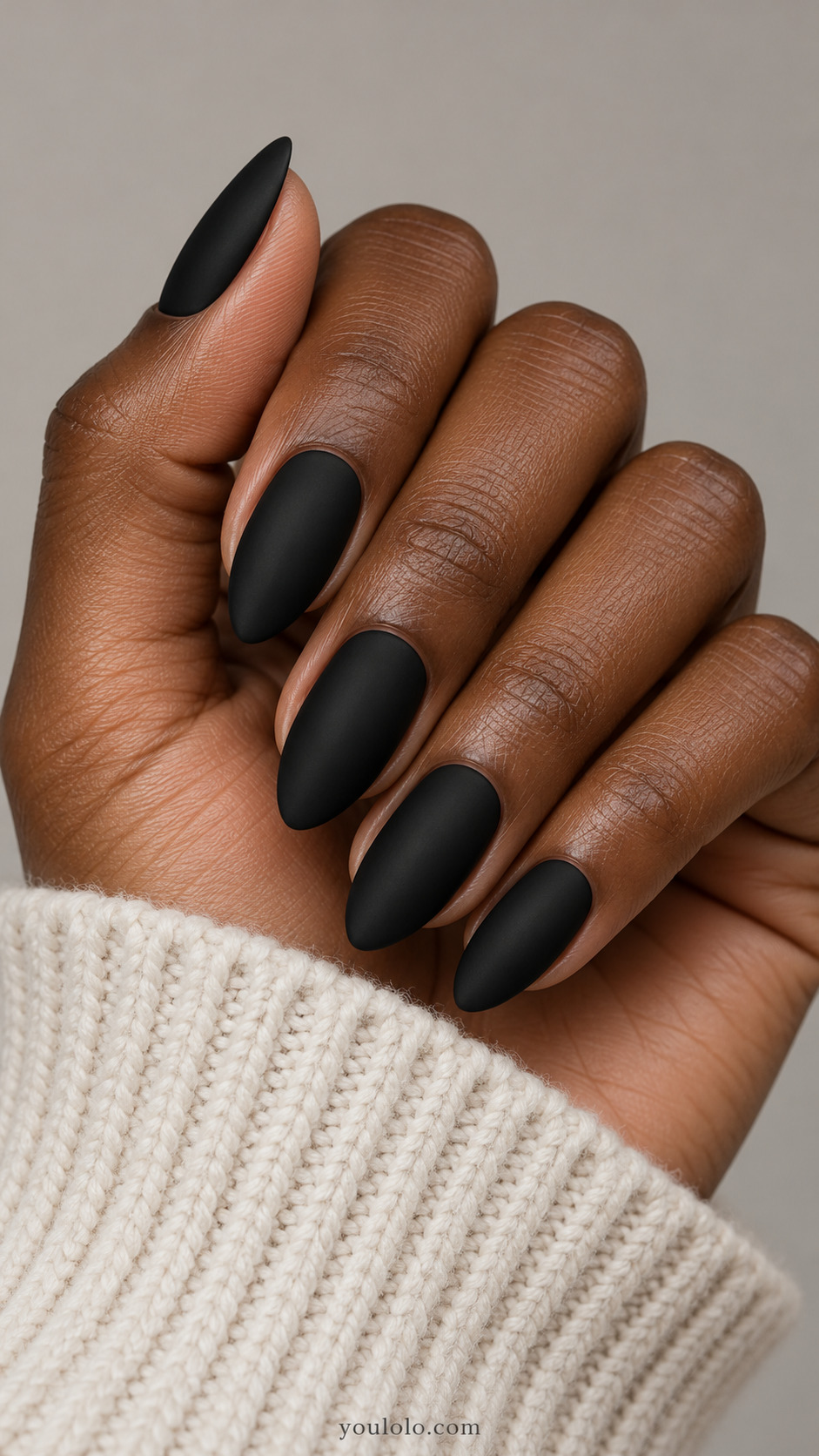 Matte black almond nails on a deep brown hand