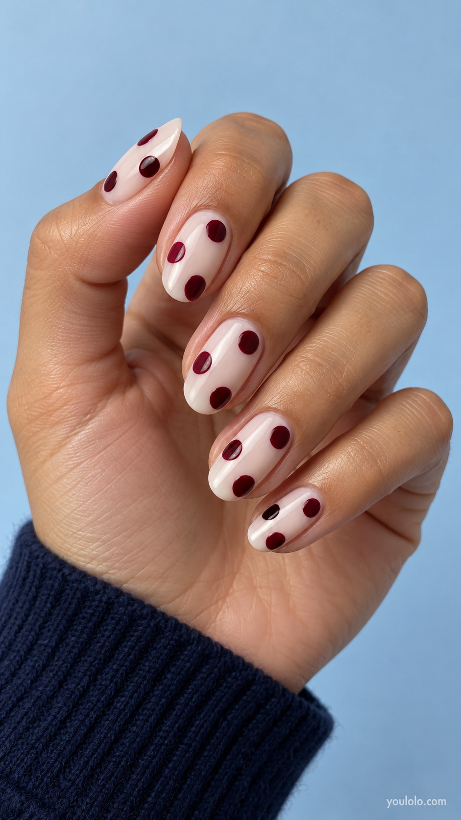 Medium oval nails, milky ivory base, bold burgundy circular polka dots, generous circles leaving much open space.