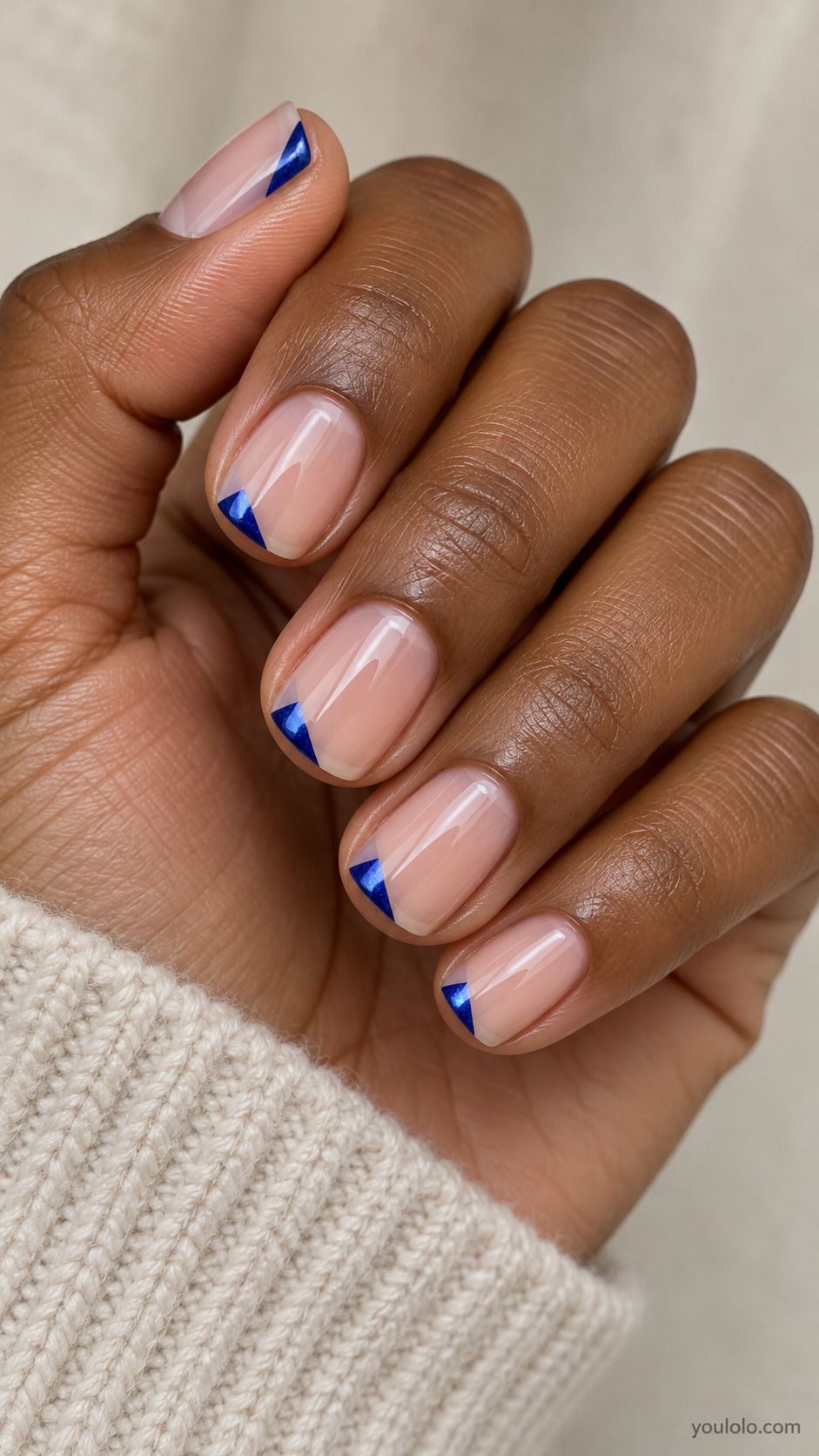Tiny Sapphire Corner Triangles on a softly gathered feminine hand with detailed sapphire blue manicure