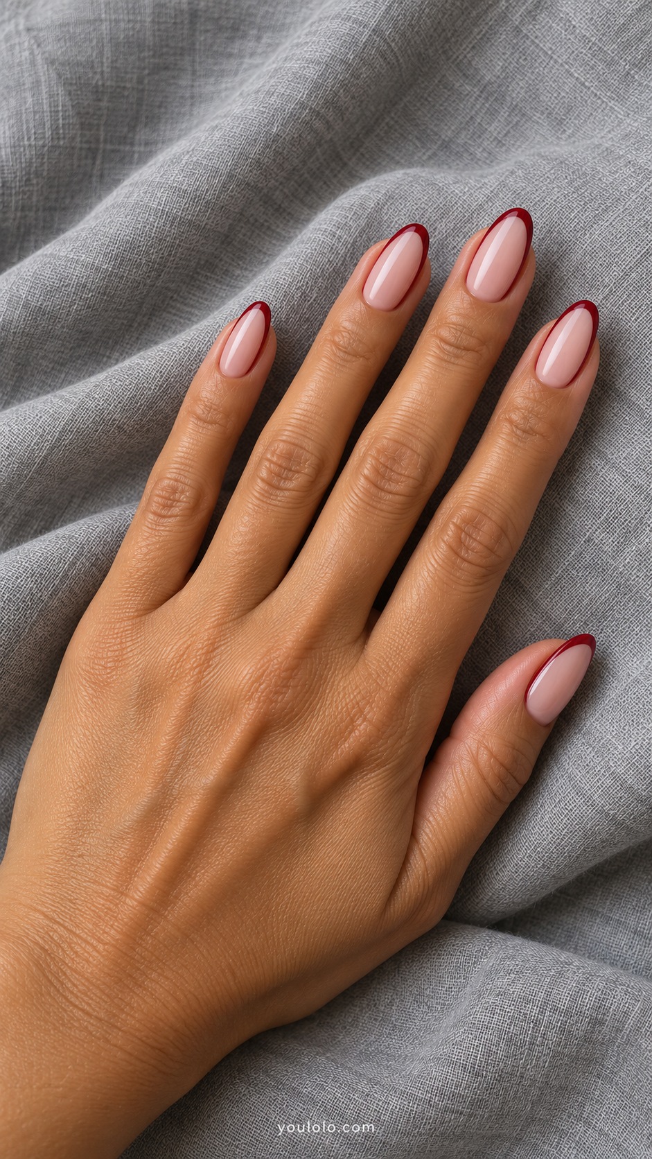 Medium oval acrylic extensions nude pink center with narrow cherry red perimeter border on every nail