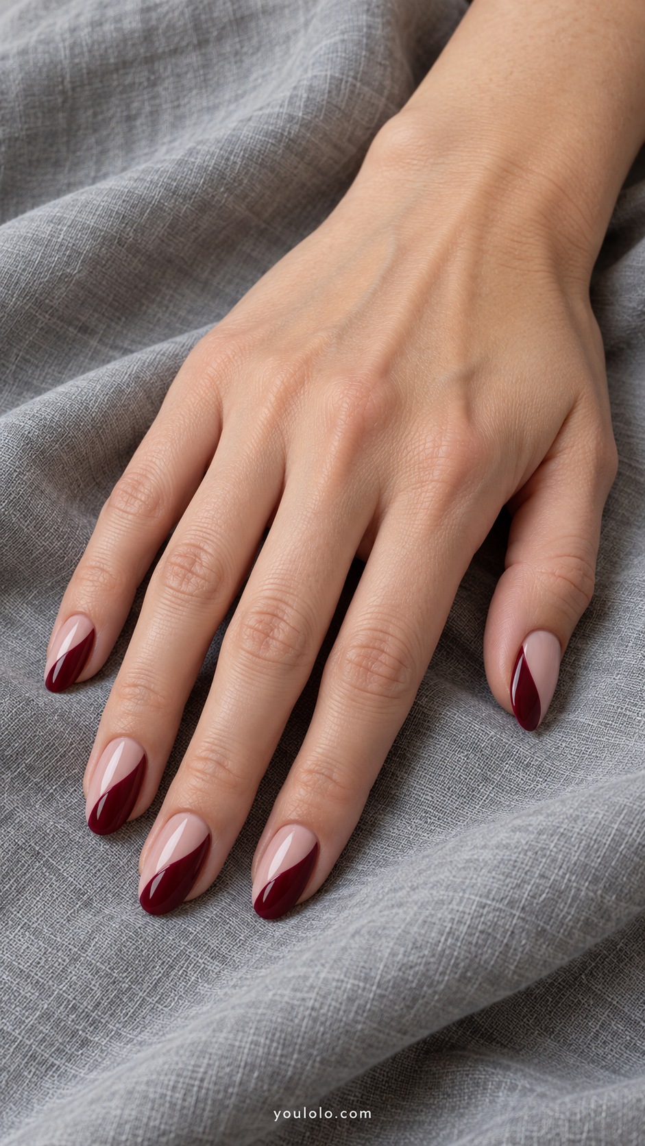Medium almond nails blush base with wide oxblood curved arches rising from one side