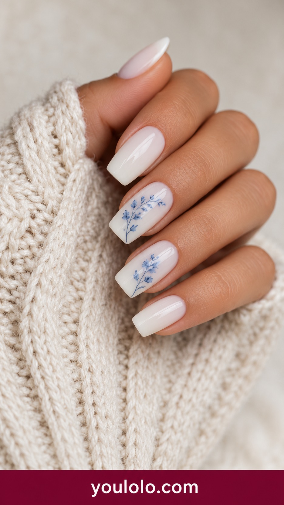 Medium square milky ivory nails with fine dusty blue hand painted floral sprigs on two nails, remaining solid ivory on a naturally curled young adult hand