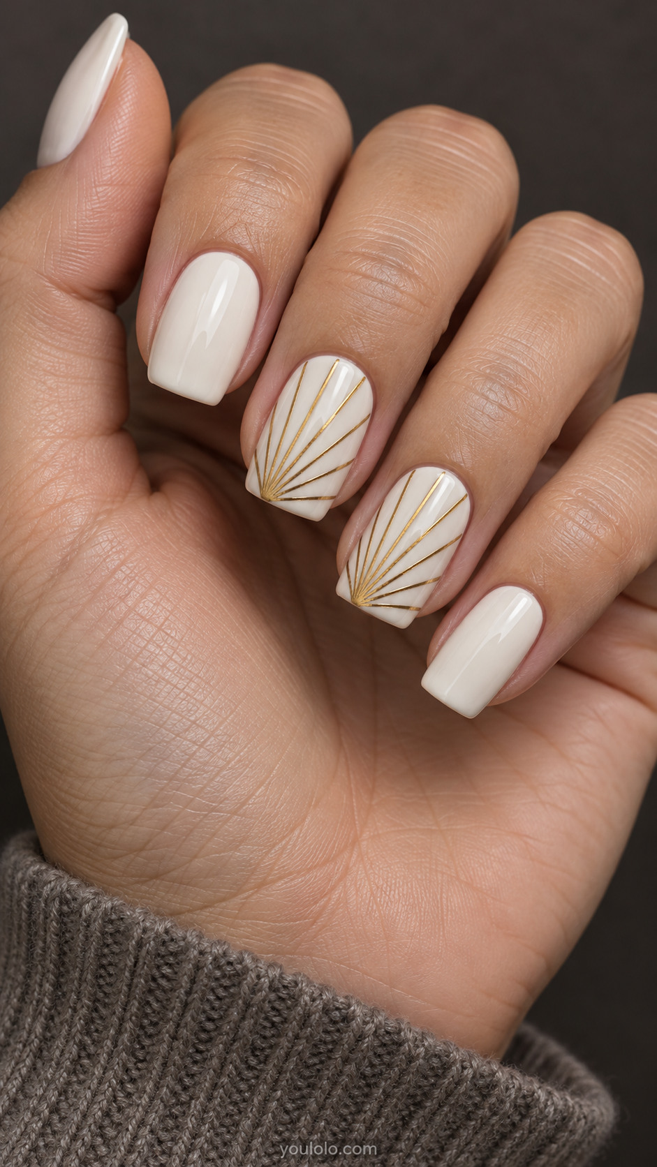 Medium square nails, ivory base, fine gold fan rays spreading from a corner of two accent nails