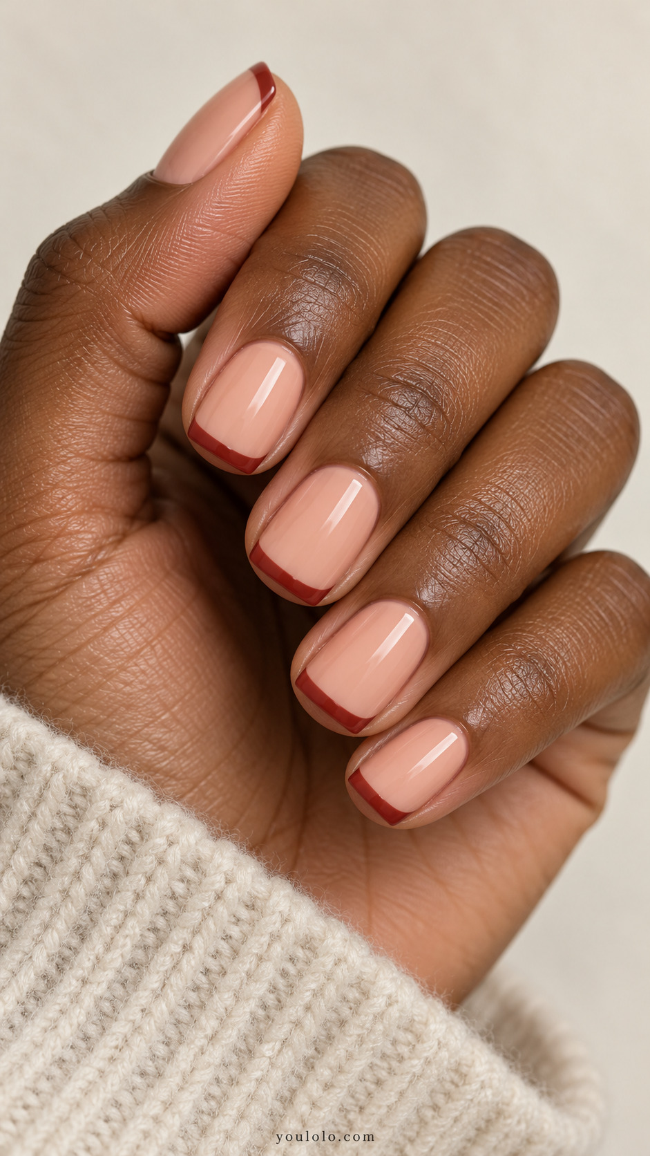 short soft-square nails, peach nude base, muted brick red thin straight French tips on a naturally gathered hand