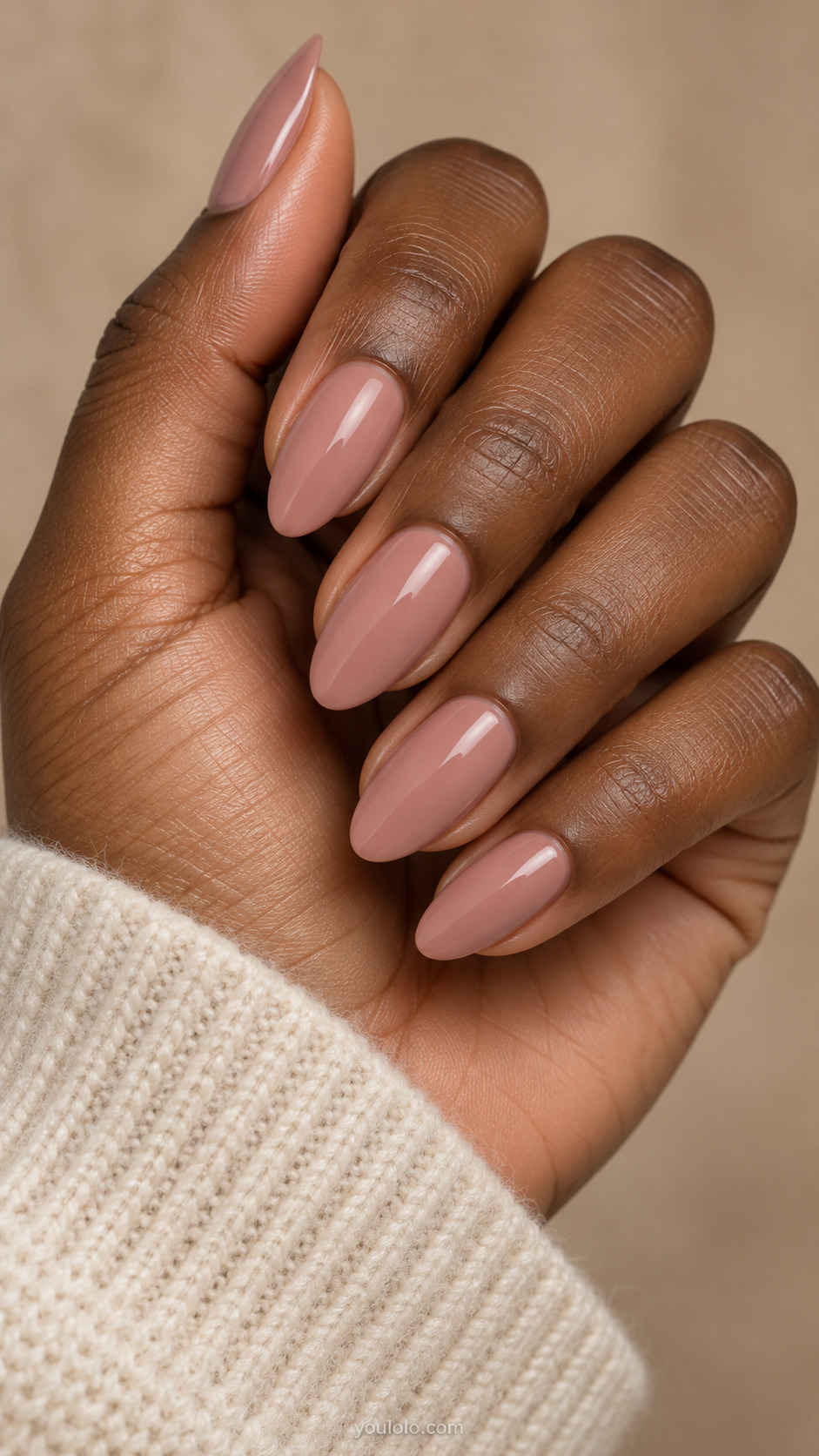 Medium almond nails painted glossy dusty rose beige beside an ivory knit cuff.
